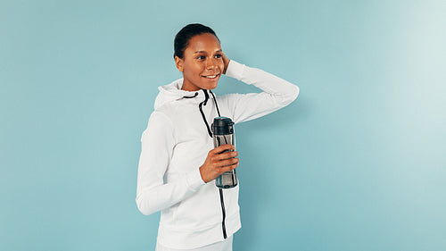 Young smiling woman posing in studio with a bottle of water