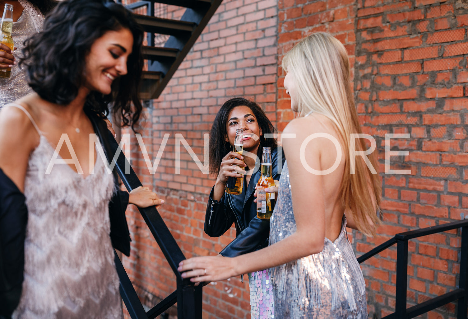 Two women toasting beers while going down the stairs in the city	