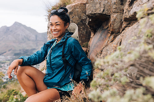 Young female sitting relaxed during her hike. Fitness woman resting after trekking.