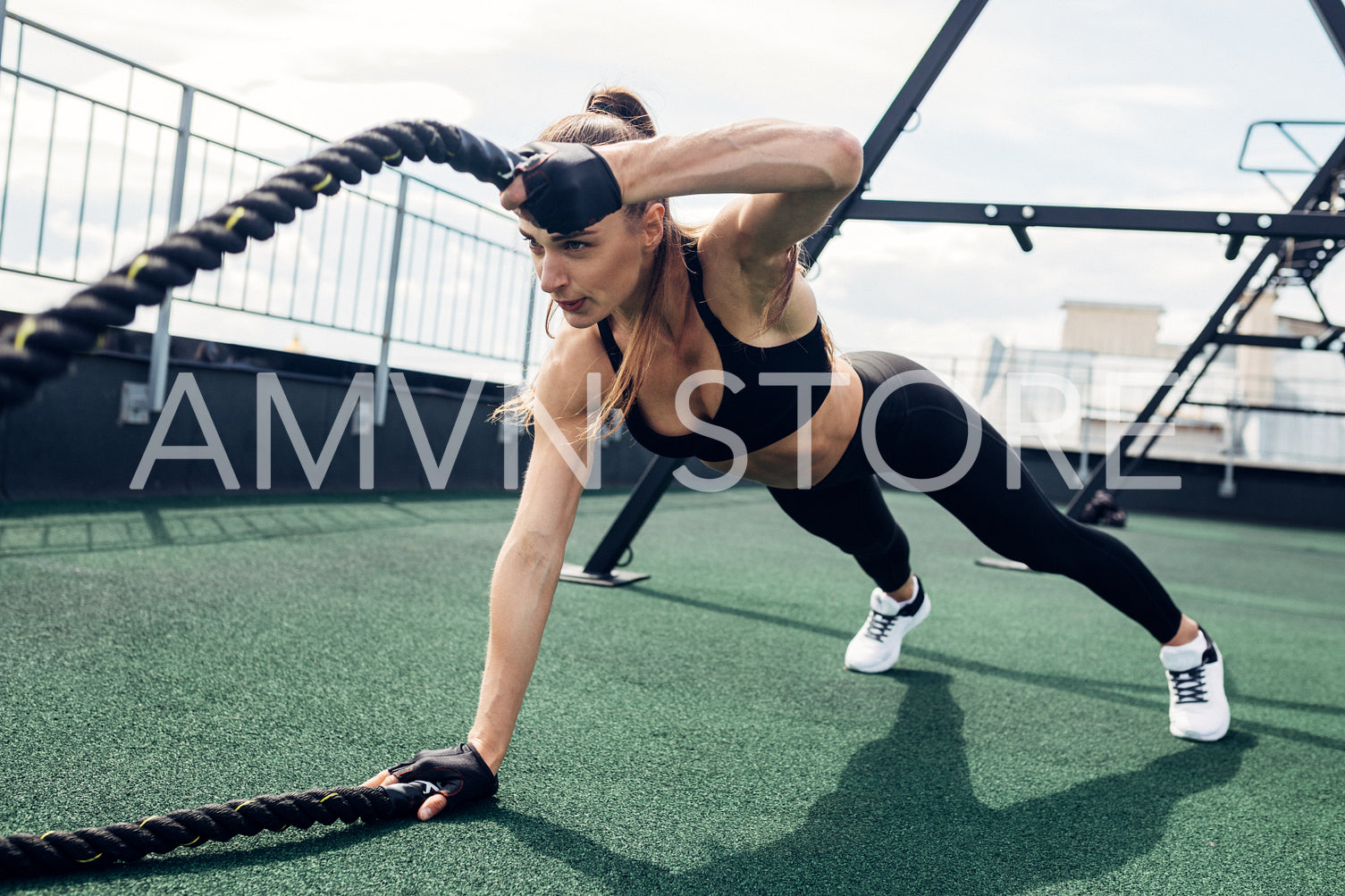 Fitness woman exercising with battle rope outdoors. Muscular athlete working out on a terrace.	
