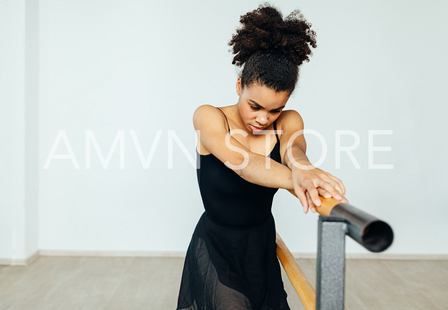 Mixed race woman in dancewear resting during exercises at the barre	