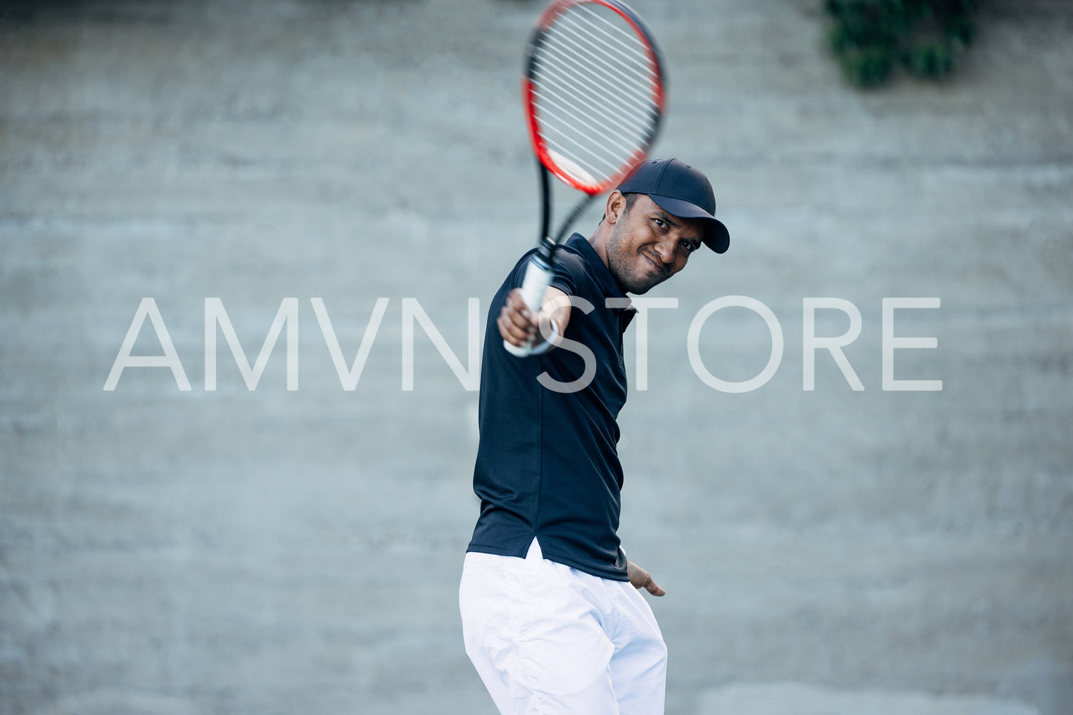 Young tennis player playing on a hard court and hitting a ball during a match