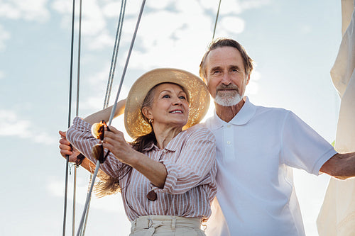 Mature couple standing on a yacht. Two stylish senior people embracing on a sailboat.