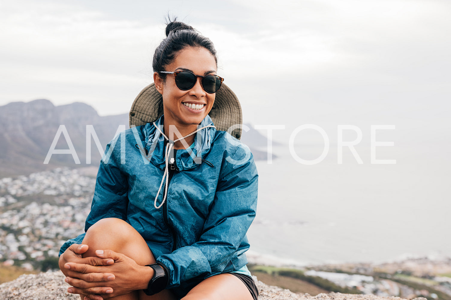 Portrait of a smiling woman hiker wearing sunglasses sitting on a rock and relaxing