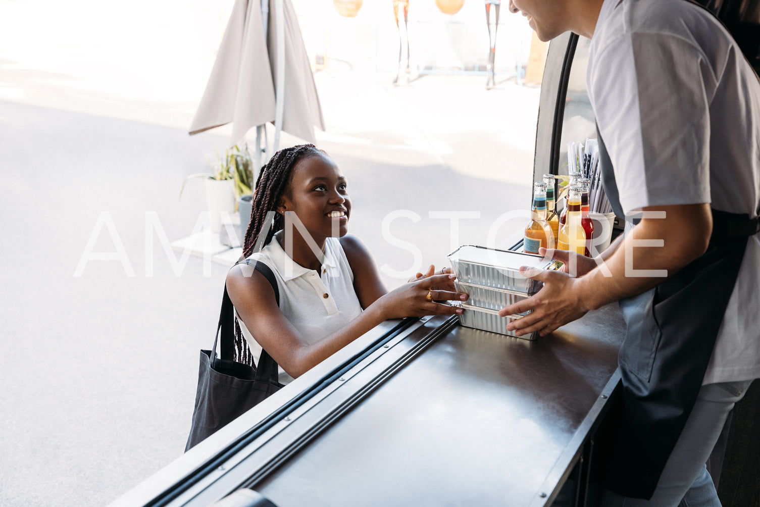 Smiling African American woman buying street food. Midsection of salesman holding takeaway packaged food.