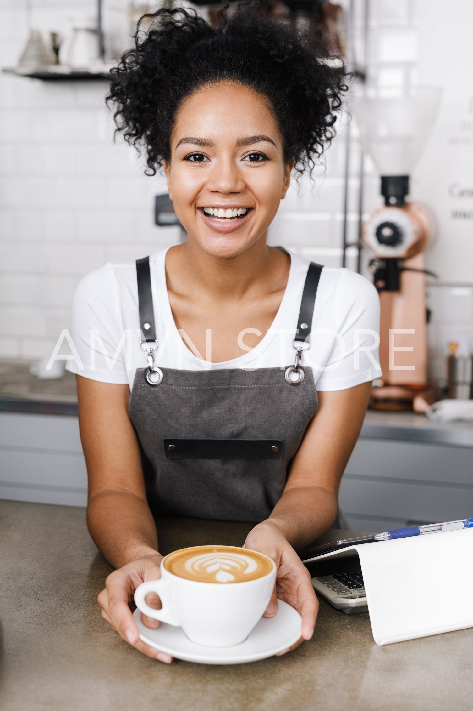 Woman barista in her coffee shop with cup of latte	