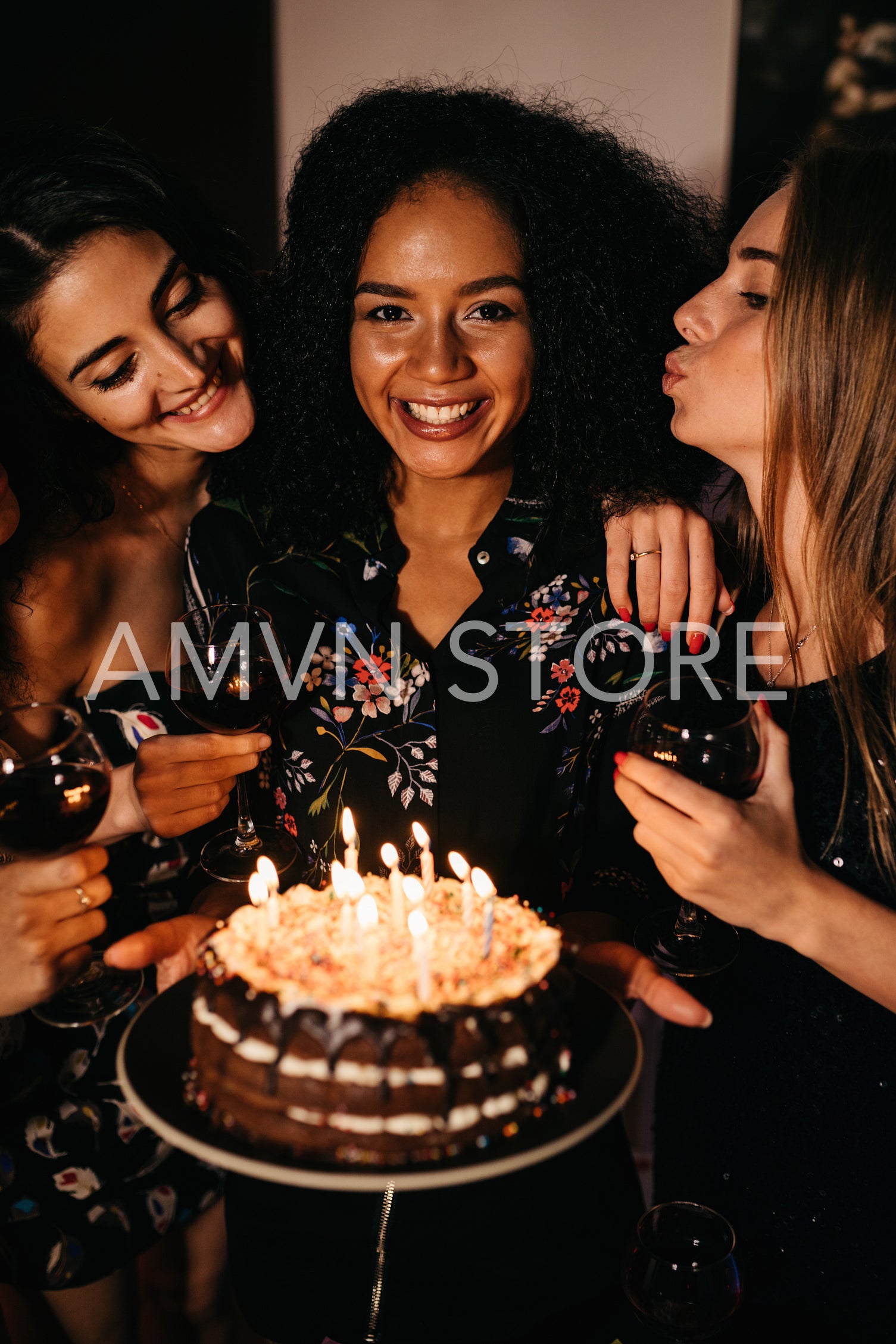 Young happy woman holding a birthday cake surrounded by friends	