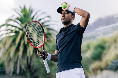 Professional tennis player wearing sports clothes holding racket and tennis ball