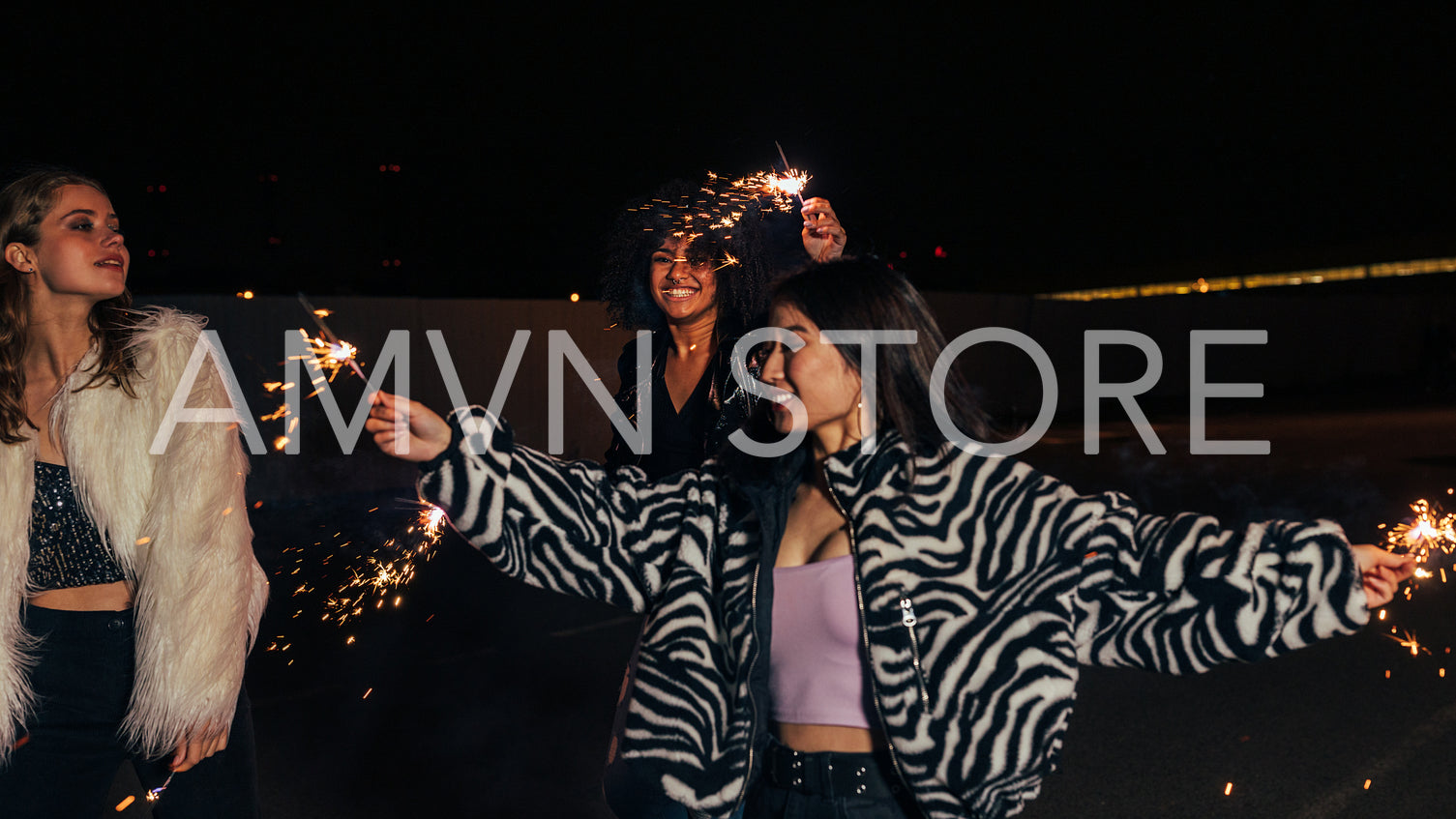 Stylish girls hanging out at night. Three young women dancing with sparklers.	