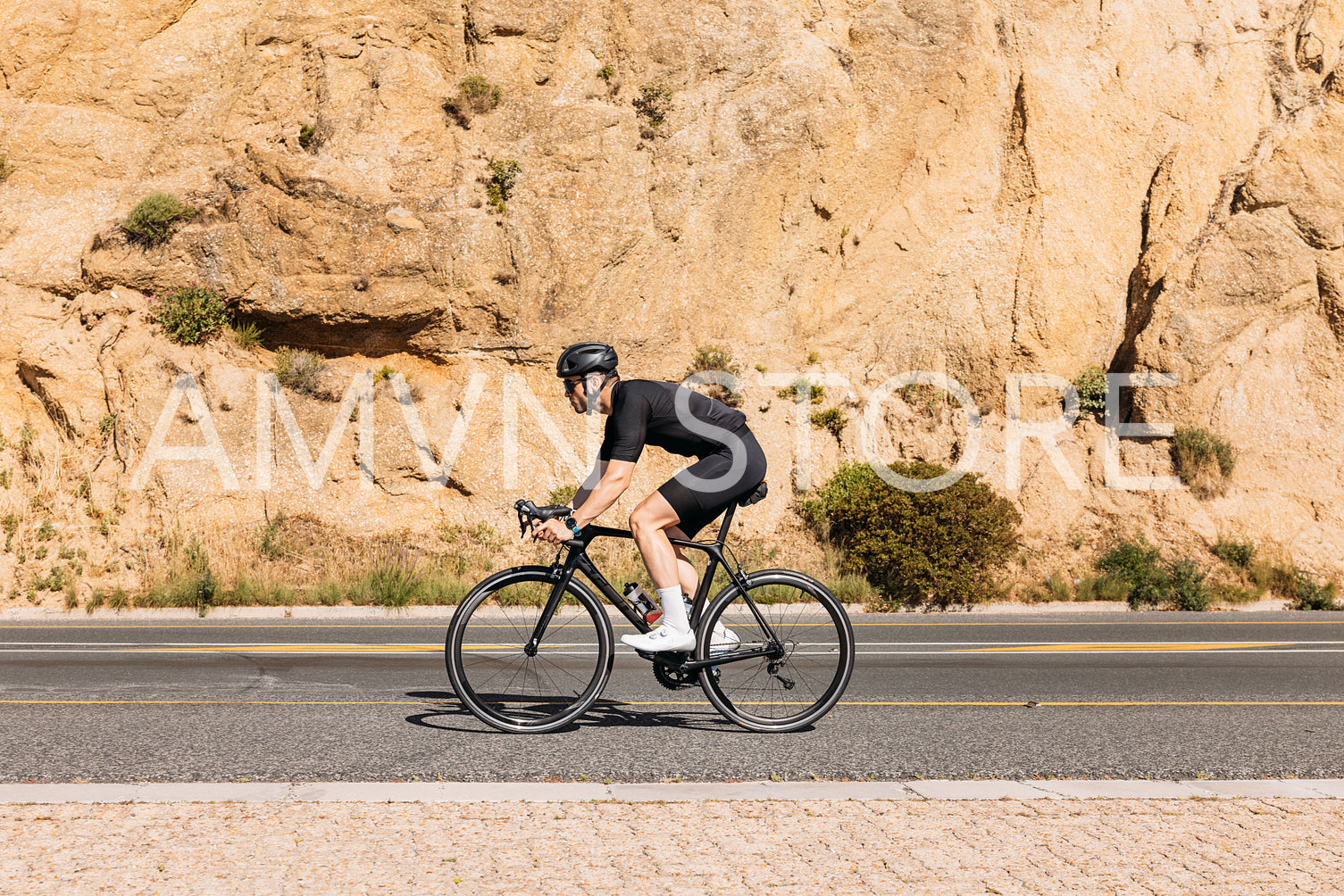 Side view of a professional cyclist in black sportswear riding bike at mountain