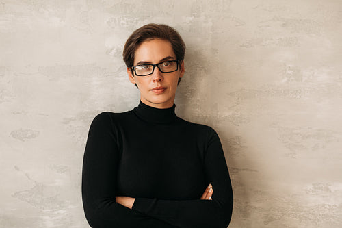 Businesswoman in formal clothes leaning on a wall with crossed arms