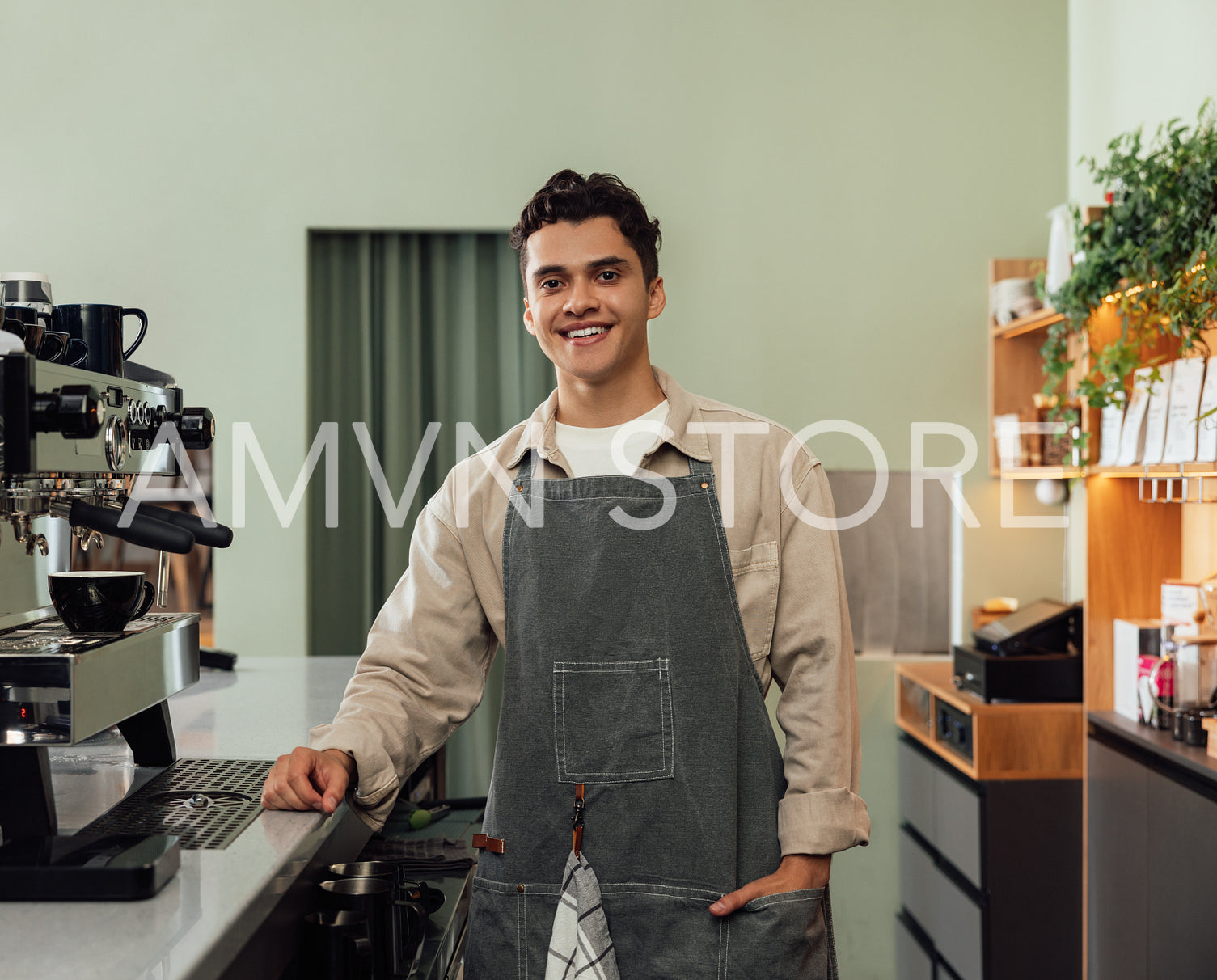 Smiling male barista in an apron looking at camera in a cafe