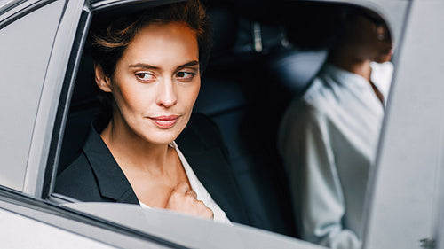 Pensive businesswoman sitting on back seat of a car and looking outside the window