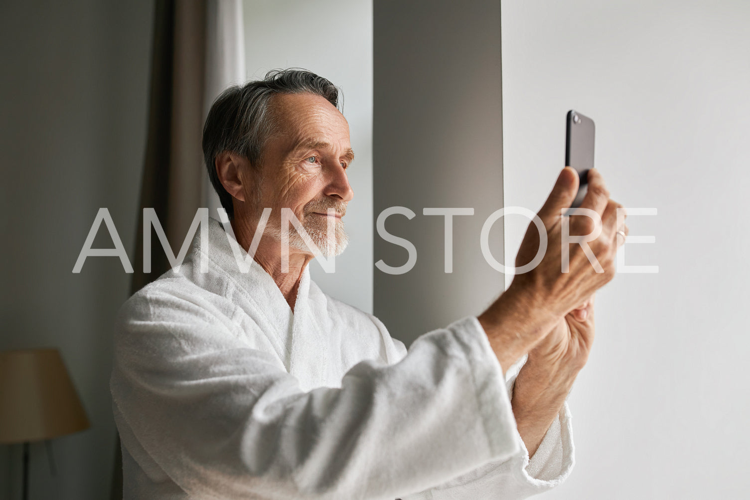 Senior man taking photographs on his smartphone from a hotel room	