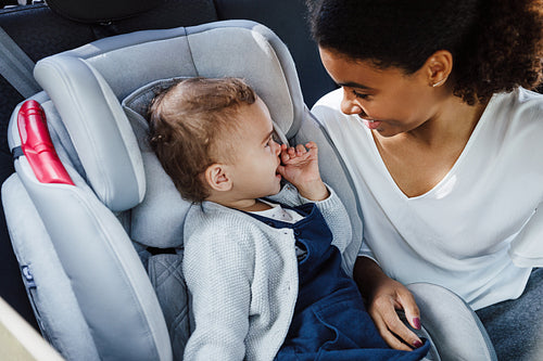 Young mother and her little daughter looking to each other while sitting in the car