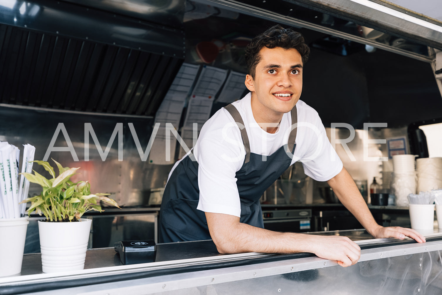 Portrait of smiling male owner wearing apron standing in food truck