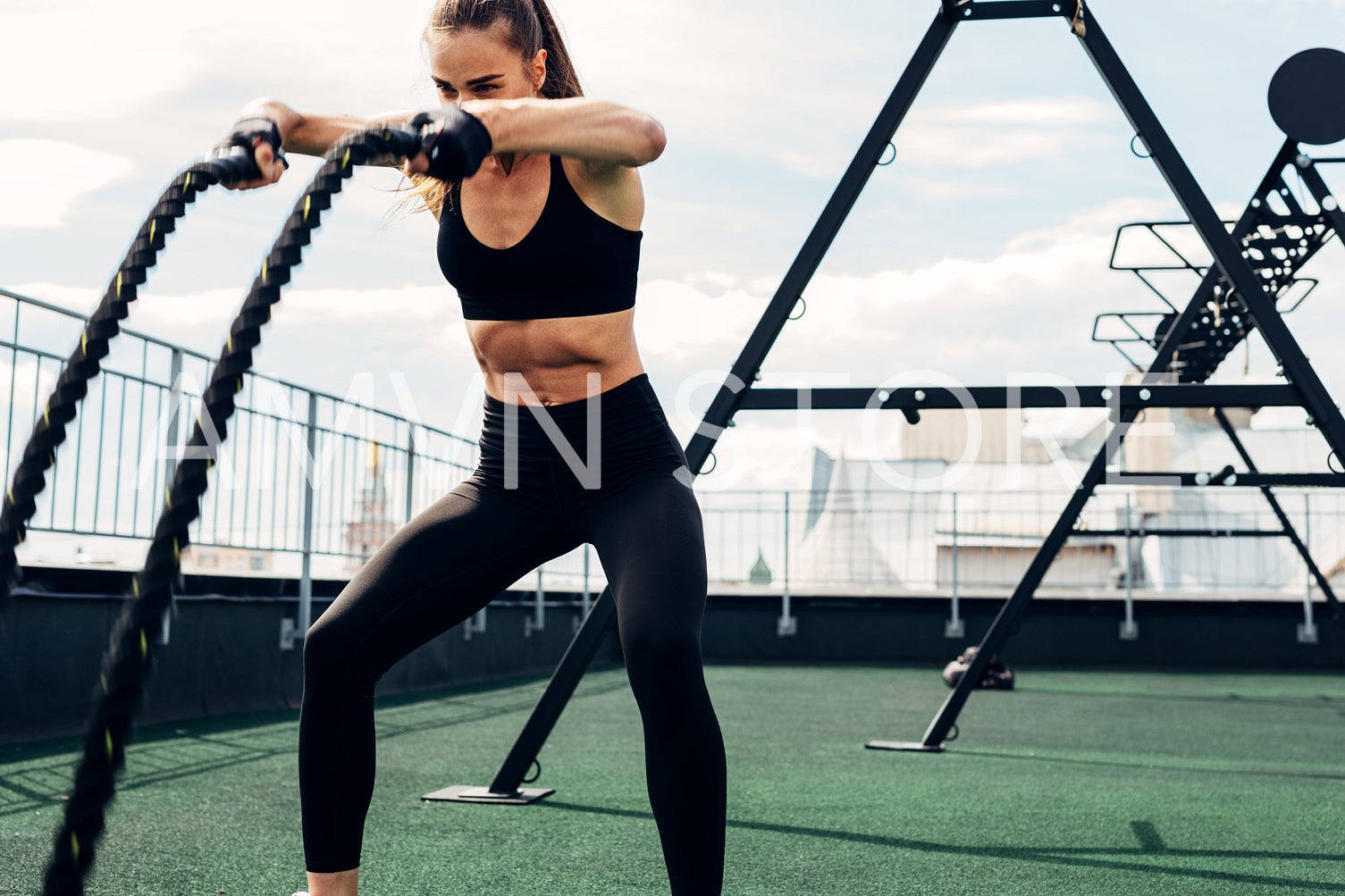 Young athlete working out with two battle ropes on rooftop	
