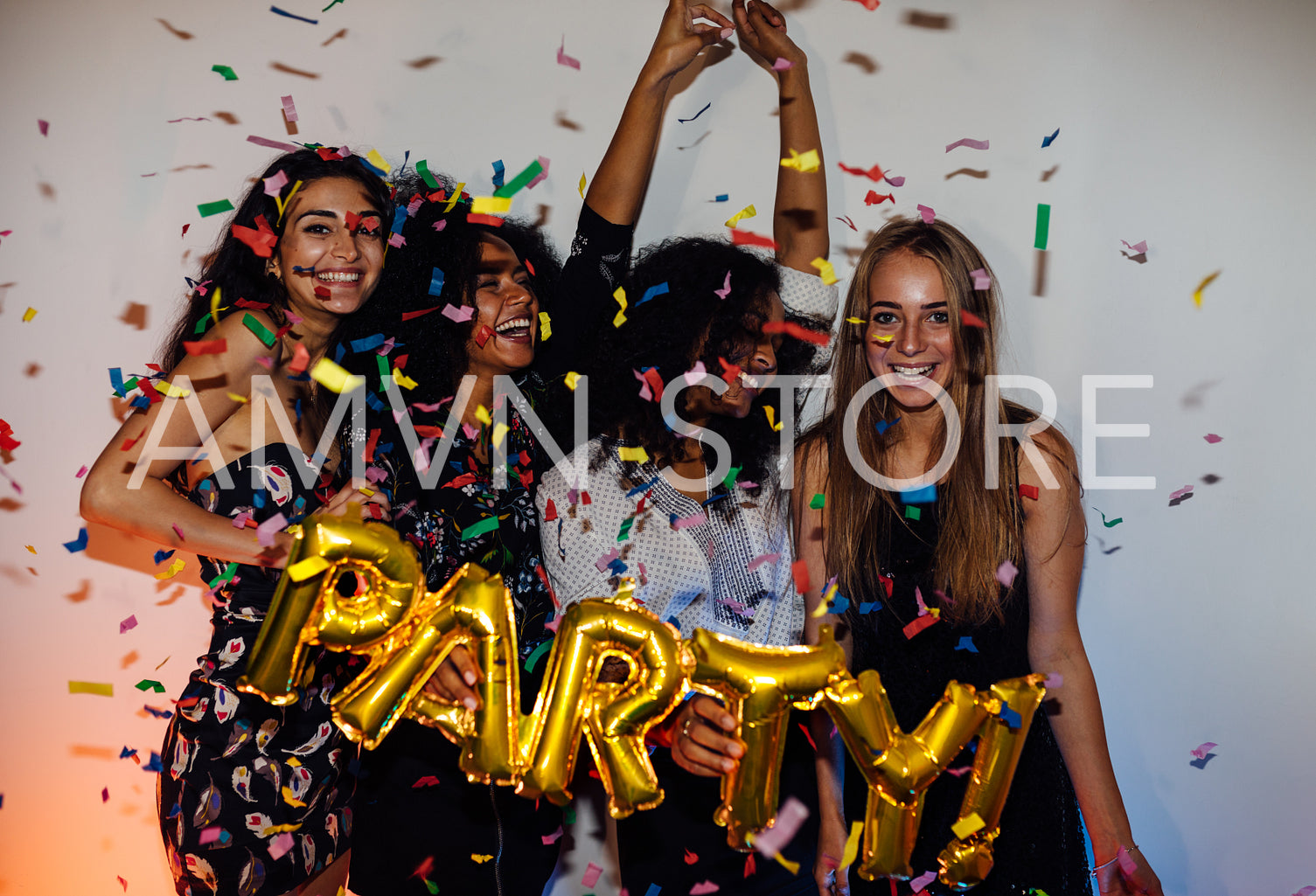 Group of young women celebrating with confetti, standing indoors	