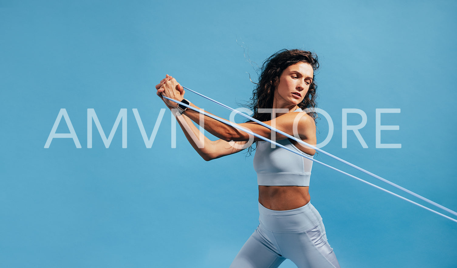 Strong woman exercising with resistance band on blue background