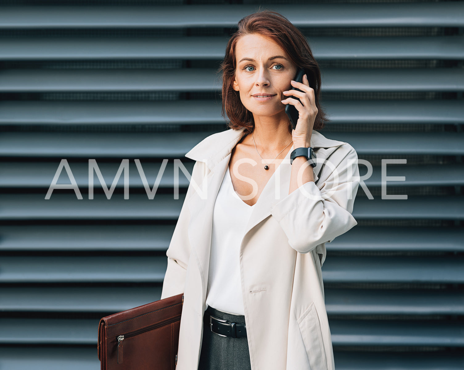 Middle-aged businesswoman talking on a mobile phone. Stylish business female with ginger hair standing outdoors.