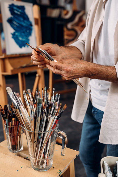 Cropped shot of artist choosing brushes in workshop