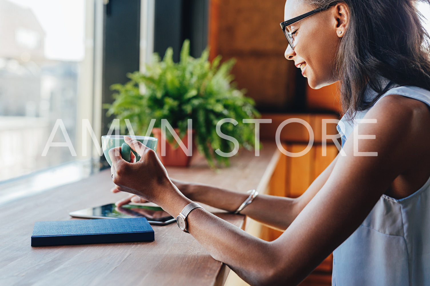 Smiling woman holding a cup while browsing files on digital tablet	