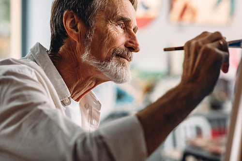 Close up portrait of senior painter drawing on canvas in studio