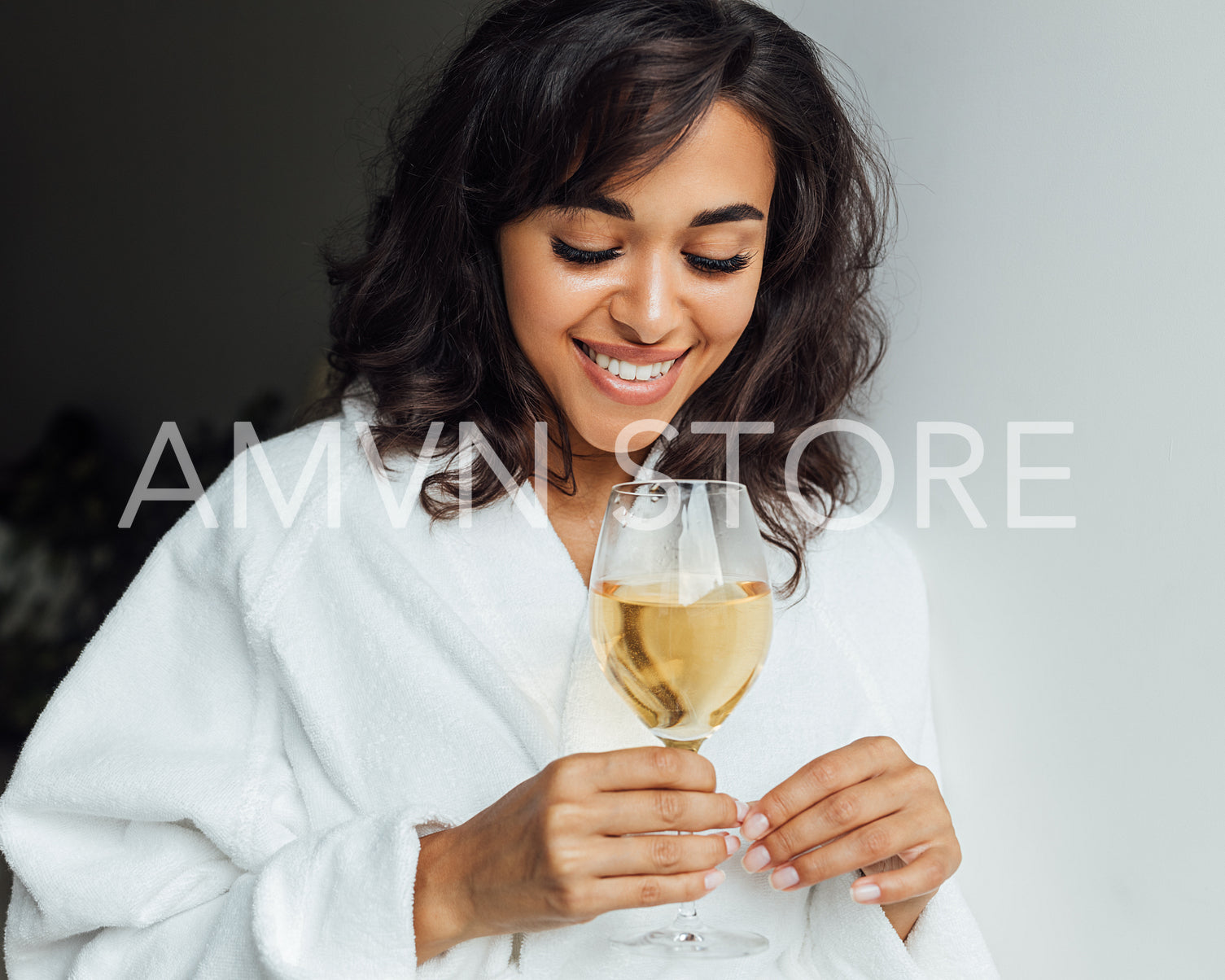 Beautiful woman relaxing at home. Smiling female looking at bocal with wine.	