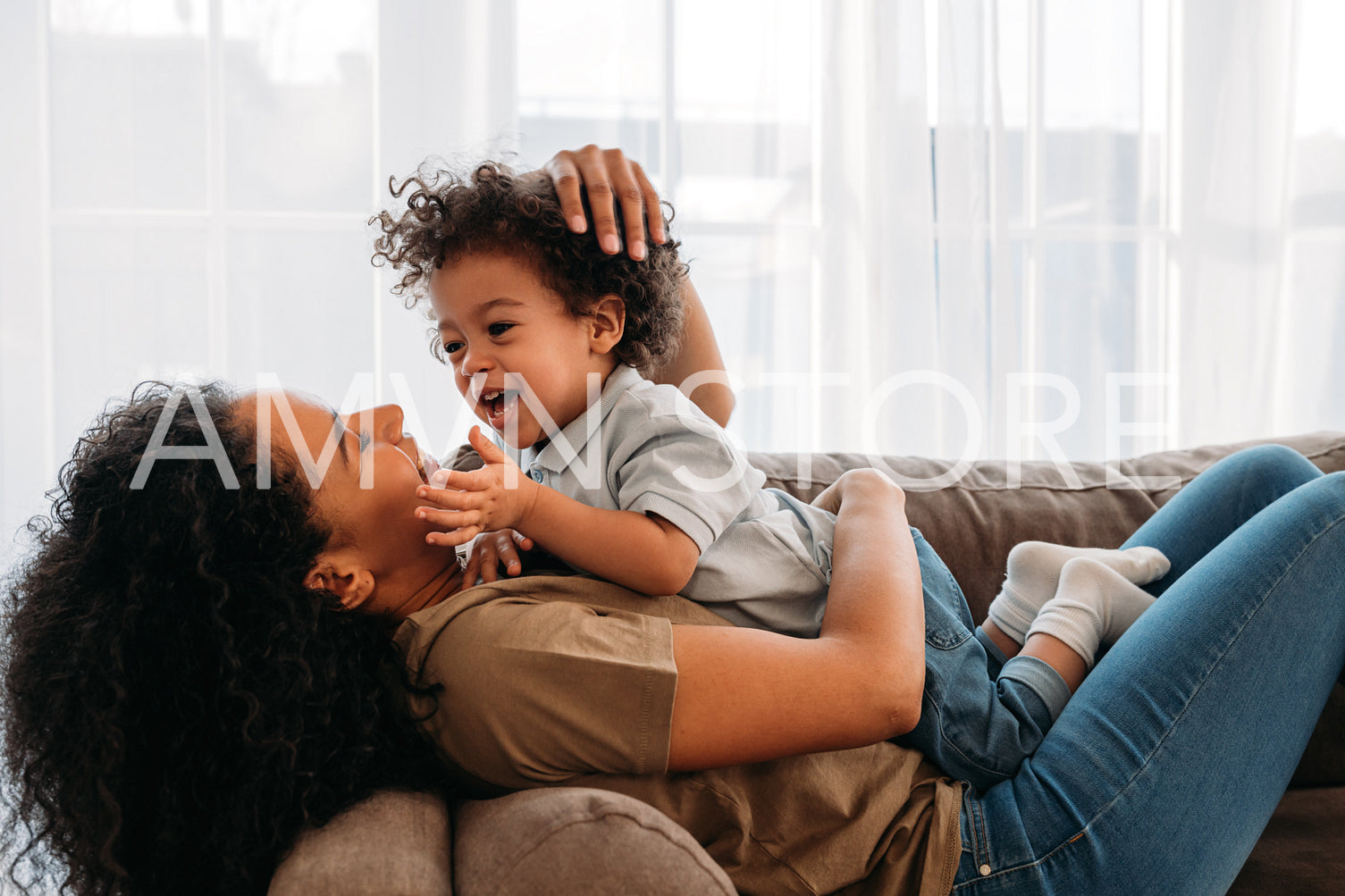 Mother playing with cute son at home. Side view of laughing boy