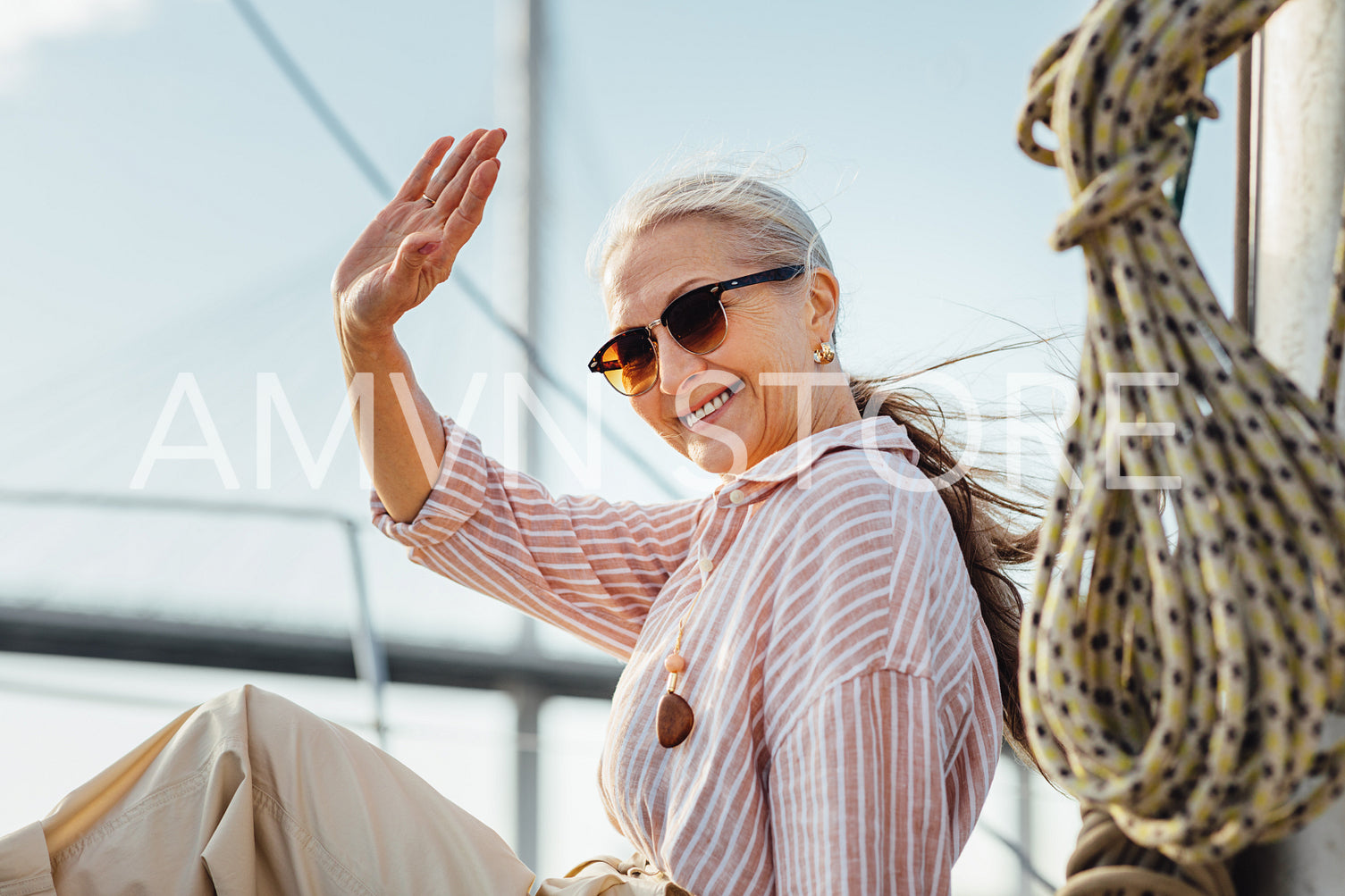 Happy woman wearing sunglasses waving her hand and looking at camera	