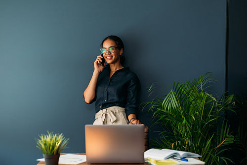 Smiling woman leaning on a blue wall. Businesswoman working from her apartment.