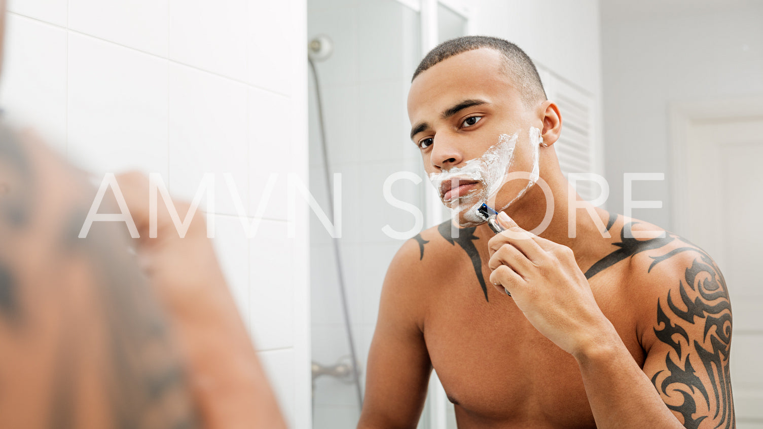 Portrait of a handsome young man shaving his facial hair in the bathroom	