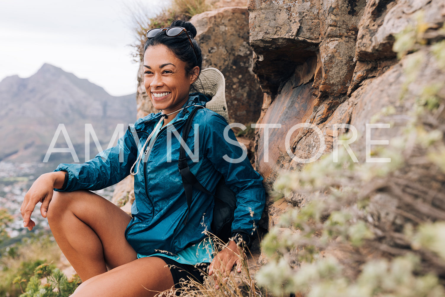 Young female sitting relaxed during her hike. Fitness woman resting after trekking.