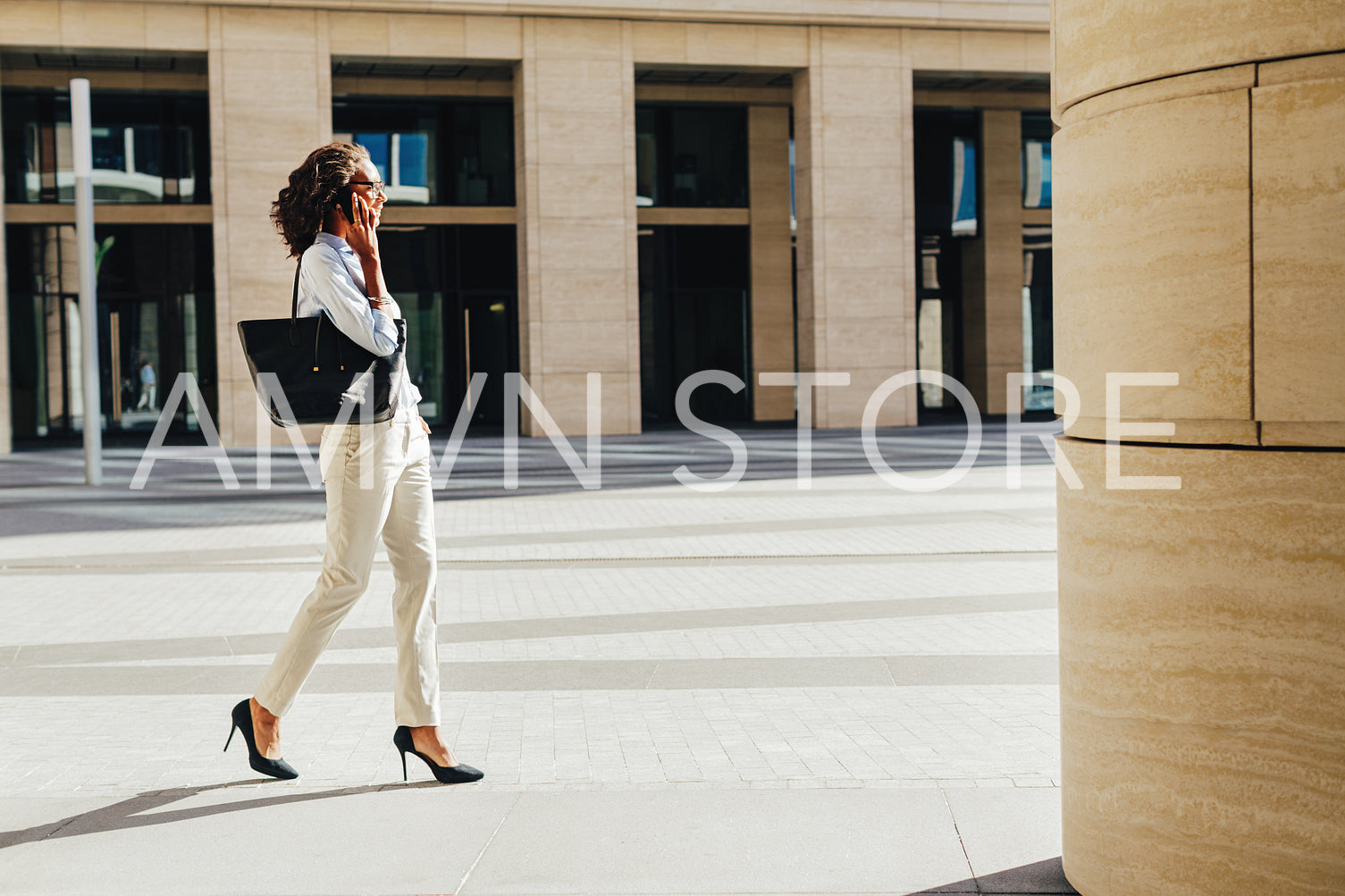 Woman carrying handbag on shoulder walking on city street from office	