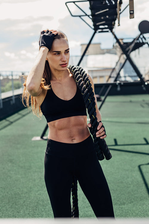 Muscular woman holding a battle ropes after intense training