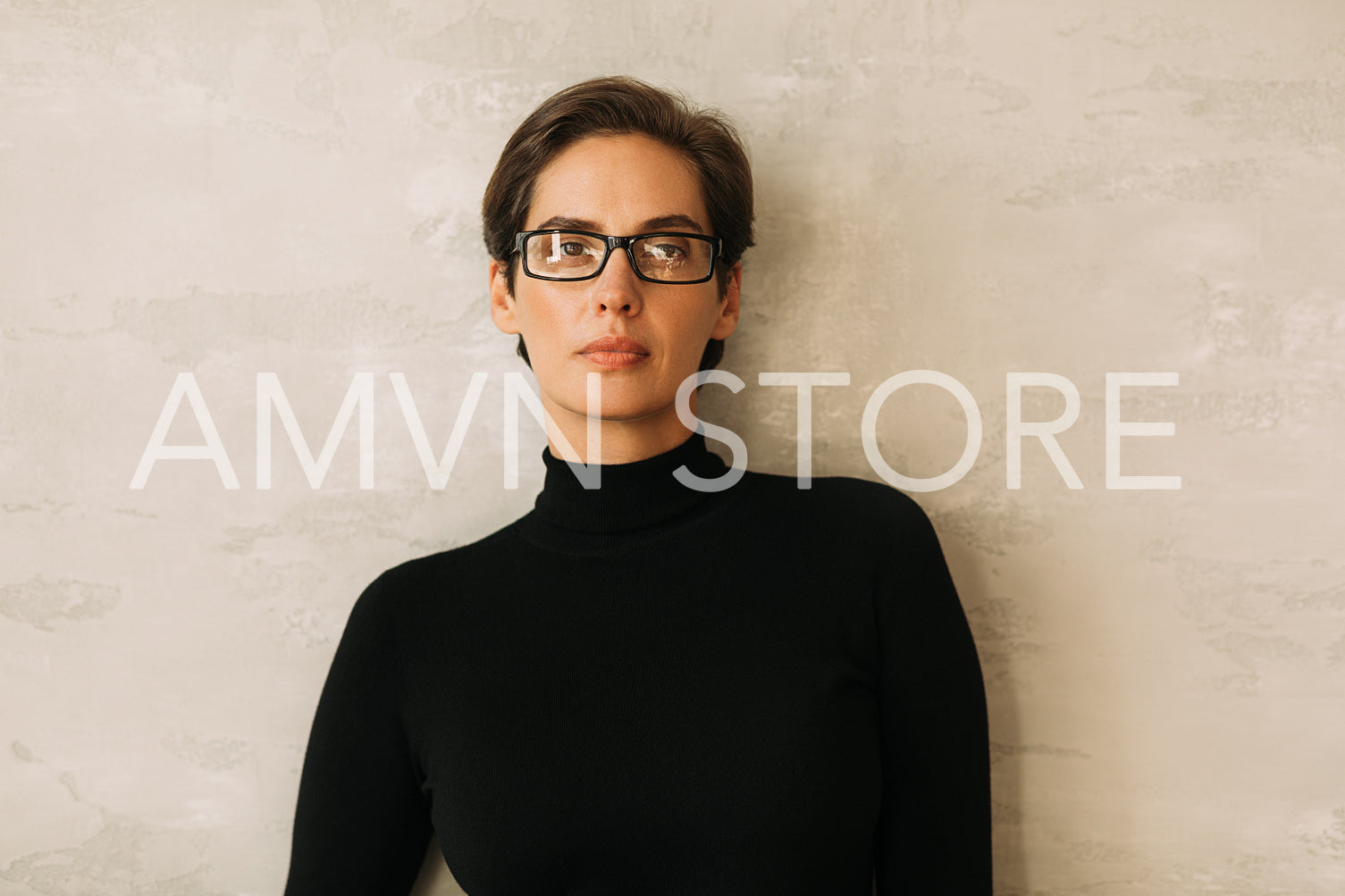 Portrait of a confident businesswoman in black formal wear looking at the camera while standing at the wall.