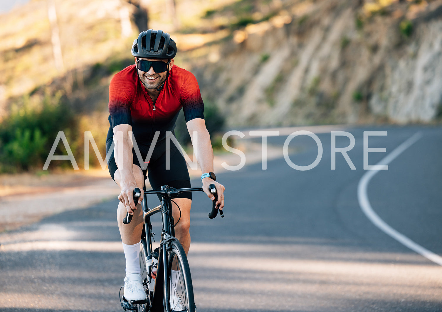 Smiling cyclist on a road bike going down a countryside road. Cheerful cyclist in sports attire.