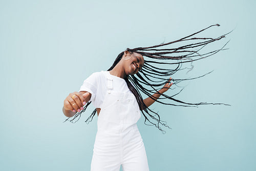 Happy female in white casual clothes flying her long braided hair while dancing