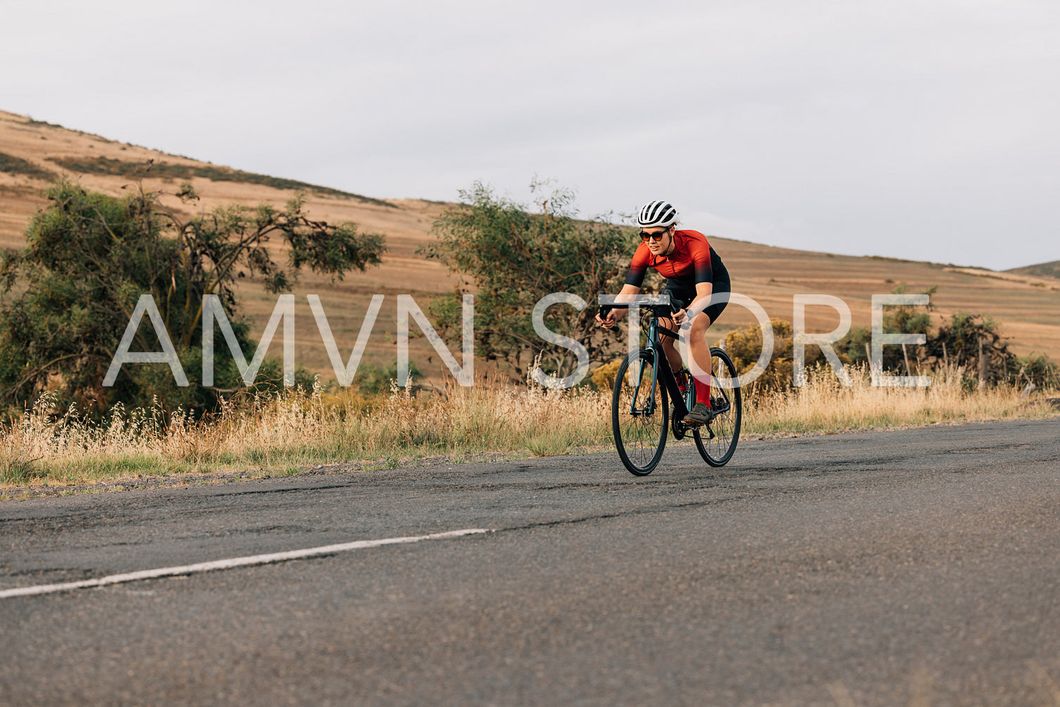 Young female riding a road bike. Woman exercising on bicycle on countryside.