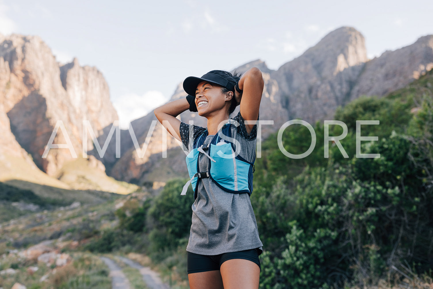 Laughing woman in sportswear relaxing during hike. Smiling female in wild terrain looking away.