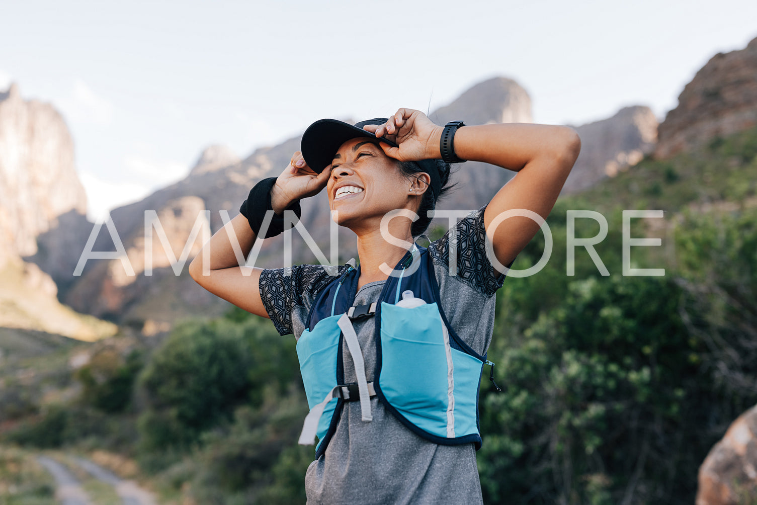 Happy woman in sportswear holding a cap looking at the mountains enjoying the hike