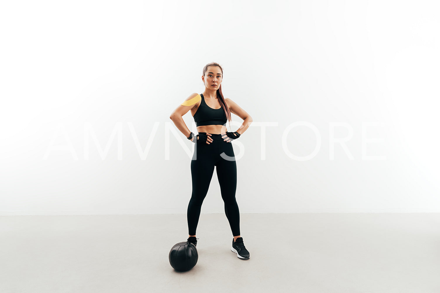 Female athlete wearing gloves resting after exercises with medicine ball