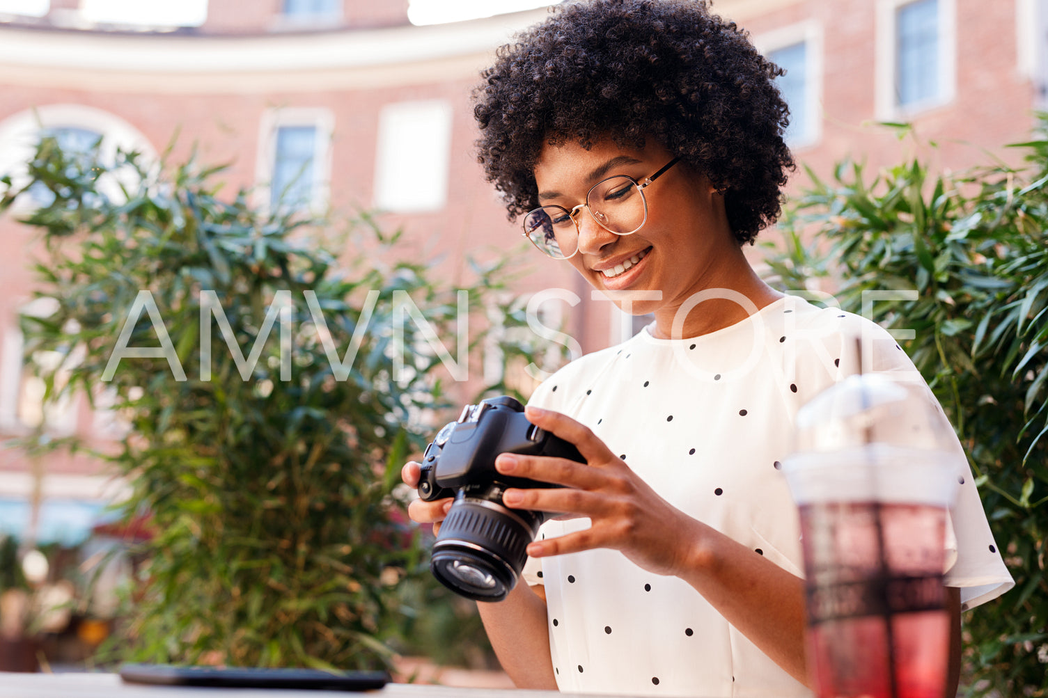 Young woman looking at digital camera while standing outdoors	