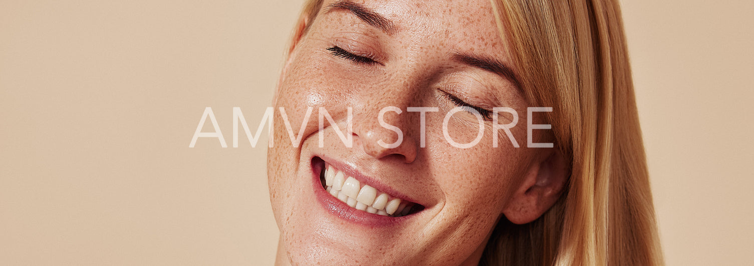 Portrait of a young happy woman tilting her head on the side. Close-up studio shot of happy female with freckles smiling with closed eyes.