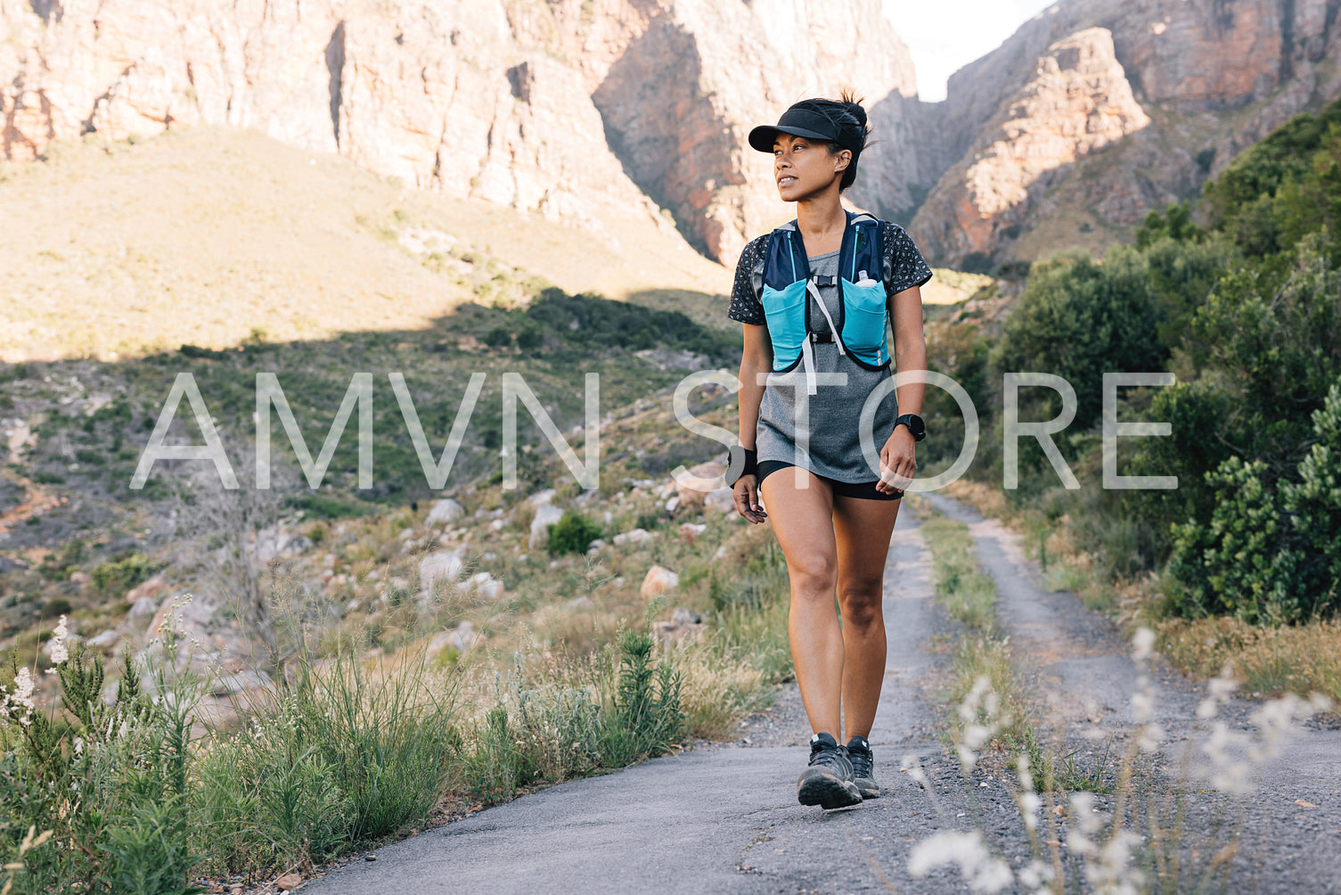 Fit woman walking on a abandoned road in valley. Female hiker looking for path.