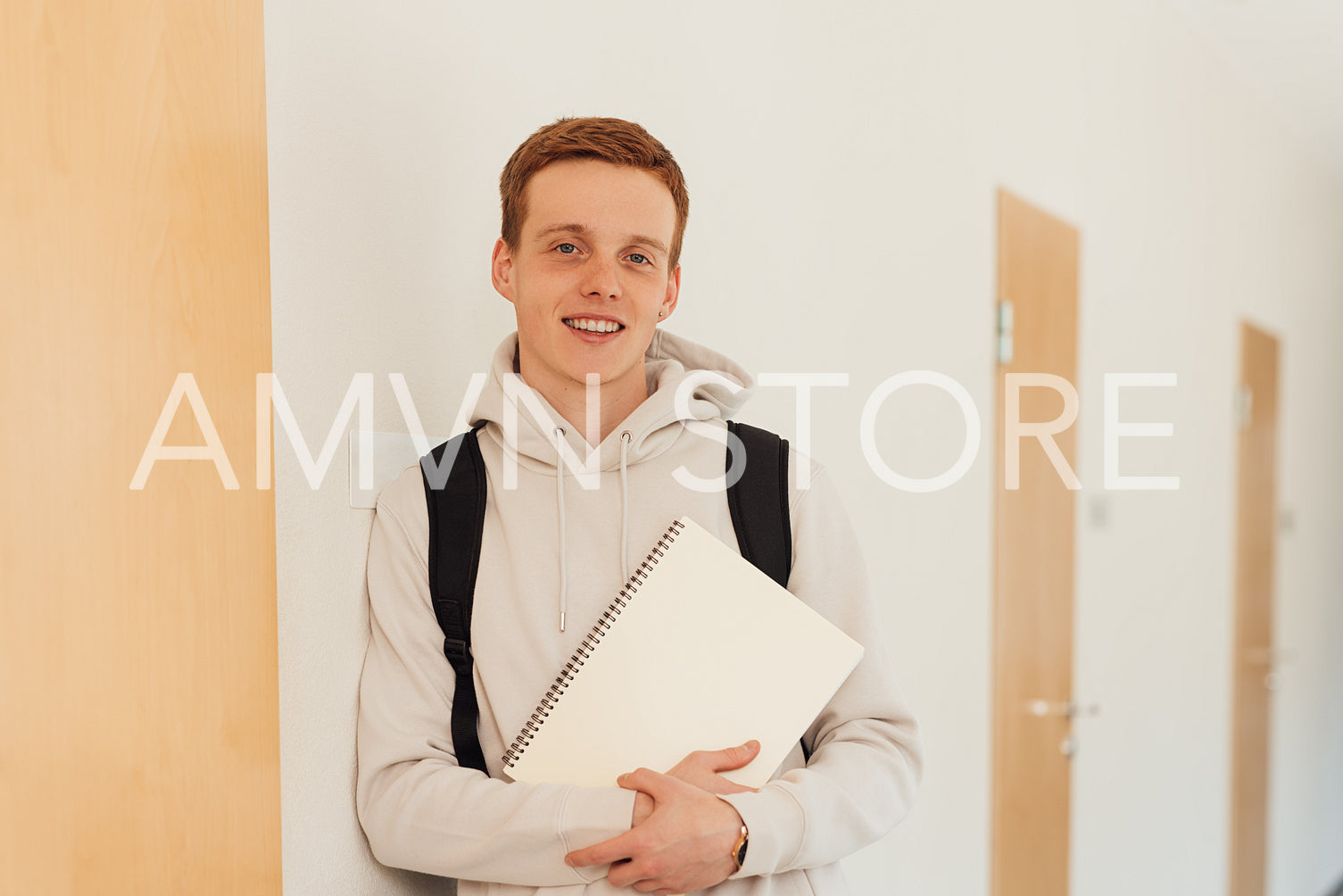 Smiling teenager leaning a wall in high school looking at camera