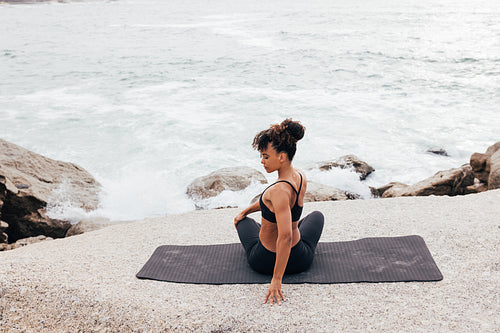 Rear view of young female athlete warming up body by ocean