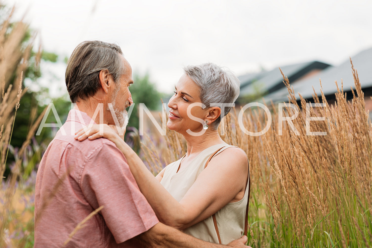 Aged couple embracing on the field. Two mature people are standing together and looking at each other.