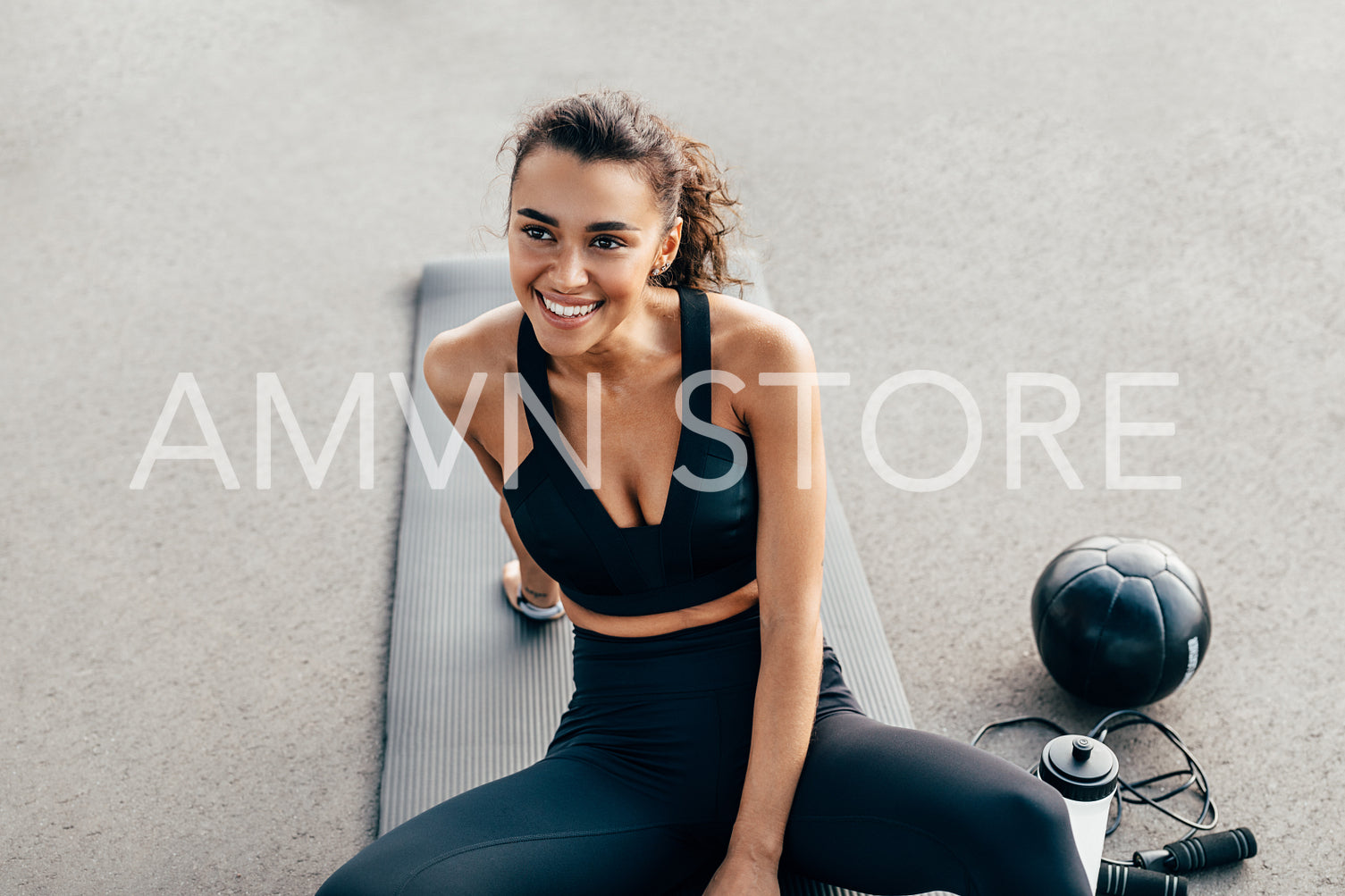 Happy fit woman sitting on a mat. Smiling female resting after workout.	