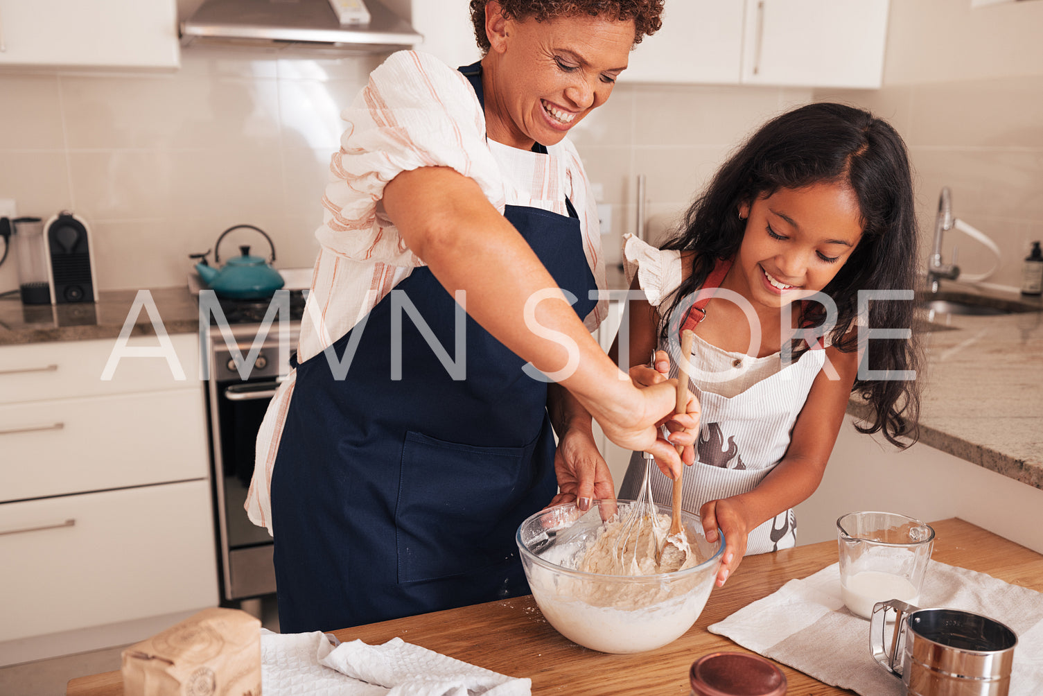 Happy grandma teaching granddaughter how to prepare batter for cupcakes